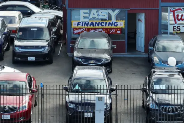 Photo of a used car lot in San Pablo, California. The office has a huge painted sign in the storefront window that reads 
"Easy Financing 
Bankruptcy
OK
Repossession
OK
SSI
OK"

Credit: Justin Sullivan/Getty Images