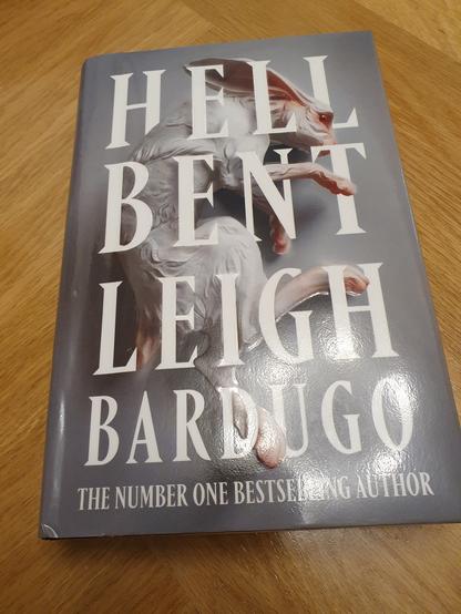 Book on the table. Theres's a white rabbit, grey backround and text Hell Bent. Leigh Bardugo. The number one bestselling author.
