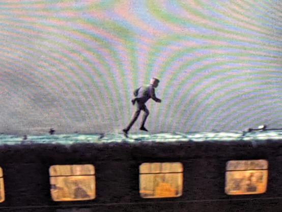 a closeup of a movie scene showing an indistinct figure on top of a train