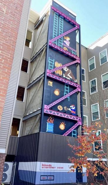 ein seitenfluegel treppenhaus, auf welchem donkey kong draufgemalt wurde, weil das stahlgerüst perfekt zum gamedesign von damals passt