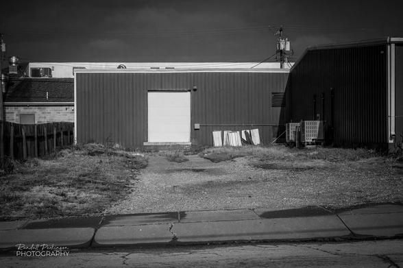 Back side of a commercial/retail building with 1 white loading dock door.