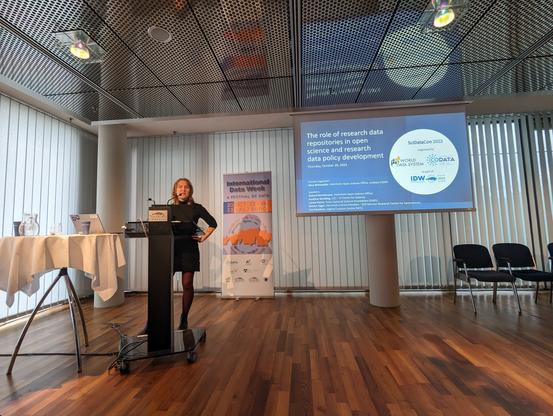 Nina Weisweiler stands in front of a screen and introduces the SciDataCon session on the role of research data repositories in open science and research data policy development.