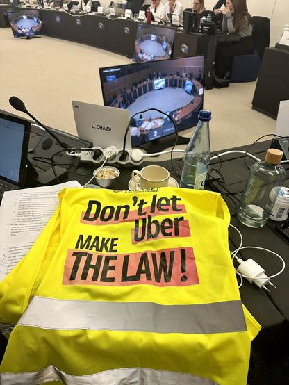 Gilet jaune avec l’inscription « Don't let Uber MAKE THE LAW ! » posé sur la table, vu depuis la place de Leïla Chaibi en commission au Parlement européen.