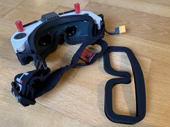 Photo, HDZero fpv quadcopter goggles on a wooden floor with a foam padding to keep it comfortable against one’s face.

A replacement foam padding sits next to the goggles.