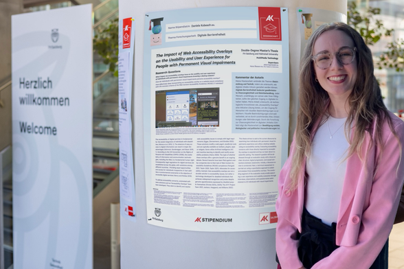 Daniela standing and smiling in front of a poster that describes her master‘s thesis, which is hanging on a wall.