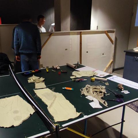 Tischtennisplatte als Ablage mit Stoff und Farbe. Im Hintergrund ein Kulissenteil mit 3 Rovern