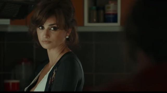 Penélope Cruz looks to her left to and back over her shoulder. She's in a dark room.