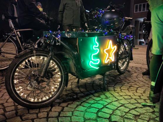 Mit Lichterketten und bunten Leuchtschlangen geschmücktes Lastenrad