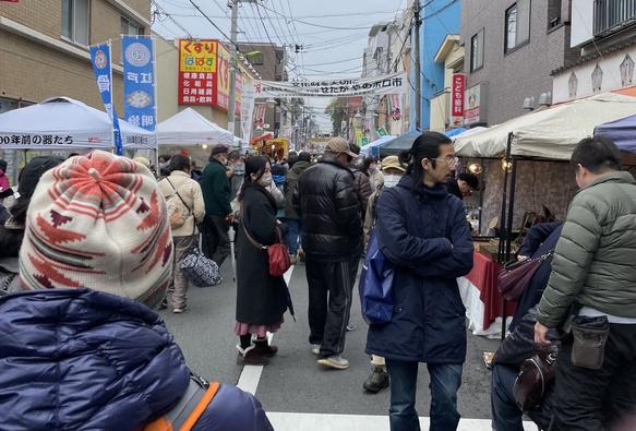 Narrow street in Tokyo crowded with pedestrians and lined on both sides by vendors’ booths.