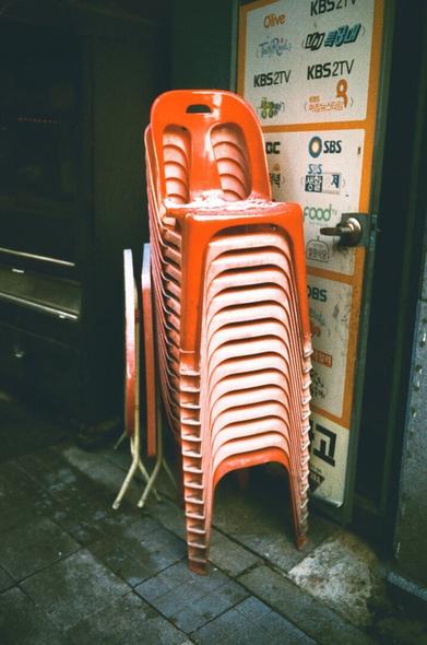 The red simple plastic chairs were stacked in layers, and the snow fell slightly on them.