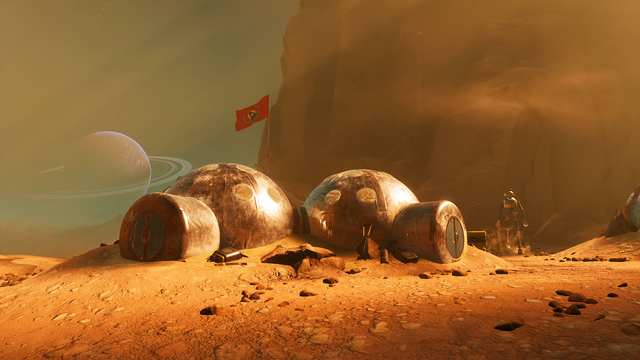 Zrzut ekranu z gry "THE INVINCIBLE" przedstawiający obóz rozbity na skalistej wyżynie przez ekipę "Ważki" na powierzchni planety Regis III. Dmuchane, pokryte termoizolacyjną folią, modułowe namioty, nad którymi powiewa flaga Wspólnoty, wyglądają na porzucone. Pośrodku obozu znajduje się unieruchomiony i, prawdopodobnie, uszkodzony Androbot AN-01.