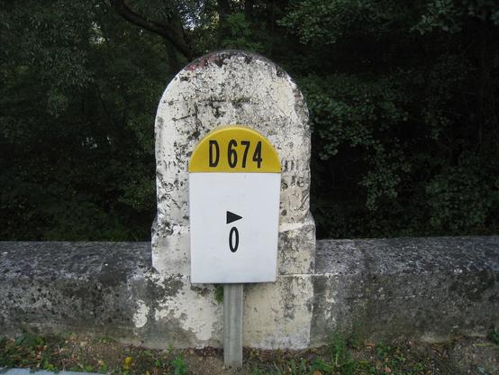 Plaque de plastique vulgaire installée devant une ancienne borne interdépartementale en pierre