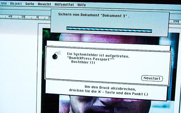 Ein Bildschirmfoto - ein echtes Foto - aus dem Jahr 1999, das einen Teil des Bildschirms eines blauen G3 Power Mac zeigt, auf dem das klassische MacOS 9.irgendwas und QuarkXPress laufen. QuarkXPress ist gerade abgestürzt und hat, wie damals üblich, das gesamte Betriebssystem mitgerissen. Dies wird über ein modales Dialogfenster mit einem "Bomben"-Symbol kommuniziert, das nur eine einzige Schaltfläche hat: "Neustart".

A screenshot – an actual photo - from 1999 showing part of a screen of a blue G3 Power Mac running classic MacOS 9.something and QuarkXPress. QuarkXPress has just crashed, and, as per usual at that time, taken the entire operating system down with it. This is communicated via a modal dialog window with a "Bomb" icon, that has only a single button: "Restart".