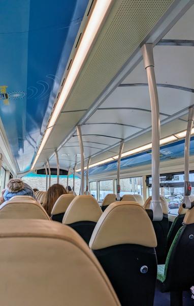 Looking down the inside of the top deck of a bus showing the rows of seats