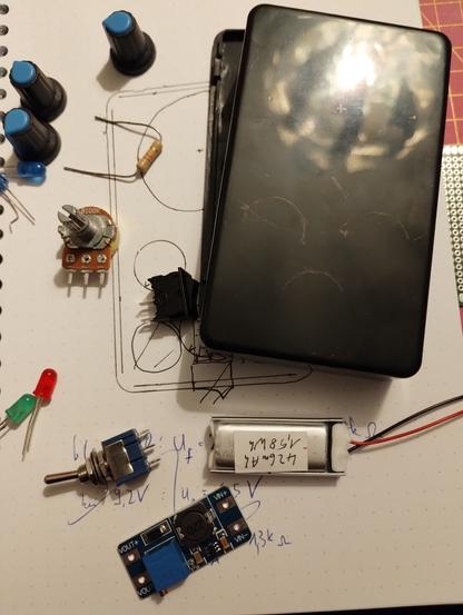 components for building the enclosure. there is a black plastic box, a LiPo battery, boost converter, potentiometer, switches and LEDs lying around