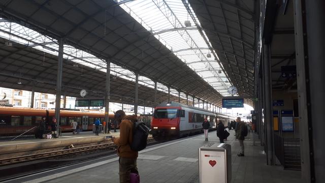 Zdjęcie z dworca w Olten: pociąg do Mainz (a w zasadzie to do Hamburga, bo taka była stacja docelowa, chociaż tak naprawdę okazało się, że jednak do Freiburga) wjeżdża na peron

Dworzec przypomina wiele innych: metalowe półokrągłe dachy, częściowo przeszklone. Pociąg jest biało-czerwony i ma "kanciastą" lokomotywę (żadne tam opływowe kształty)