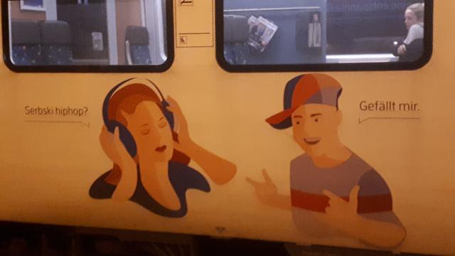 Zdjęcie boku pociągu z Drezna do Görlitz. Na pociągu namalowana jest dwójka młodych ludzi. Dziewczyna słucha muzyki i pyta "Serbski hiphop?", na co chłopak odpowiada "Gefällt mir"