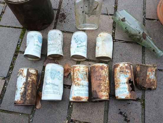 Two rows of rusty steel beer cans. Four small ones in the first row, six large ones in the bottom row.