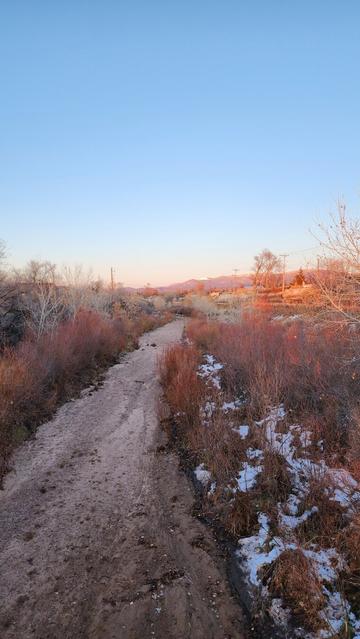 Color photo of a high desert river facing a northeastern direction - sunset is lightning distant mountains