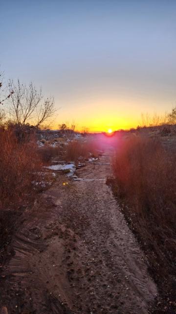 Color photo of a high desert river facing a southwestern direction - sun is setting over distant mountains