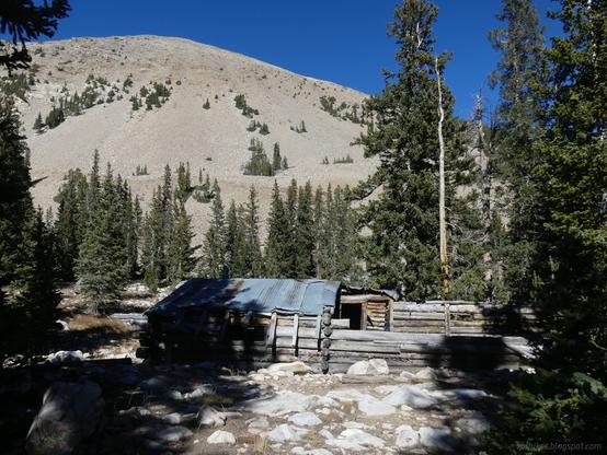 Former boarding house near Johnson Lake in Great Basin National Park, the Johnson Lake Historic Mining District.

A log cabin covered in corrugated iron and including log surrounded yard sits in front of a domed mountain. Trees, conifers that are not very dense, surround the cabin and occupy a few clumps on the mountain.