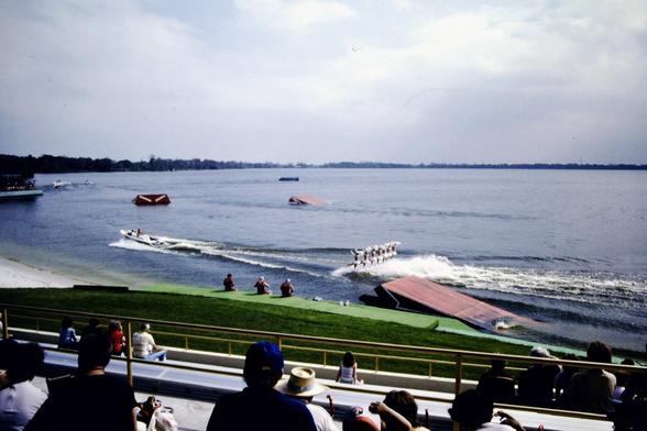 This is a view of a water ski show from bleachers along a lake.
