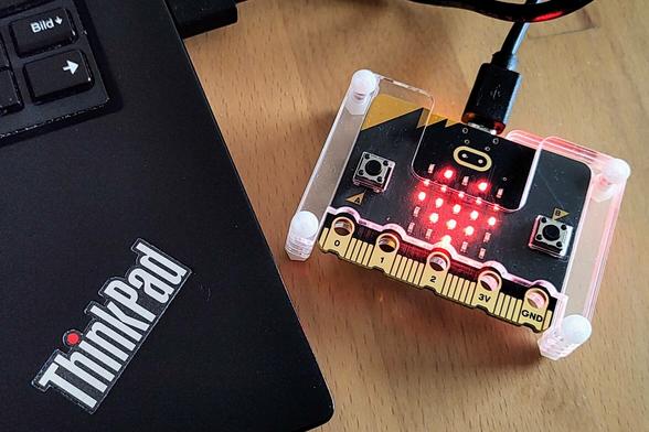 BBC micro:bit showing a heart on its 5x5 LED screen, next to a ThinkPad