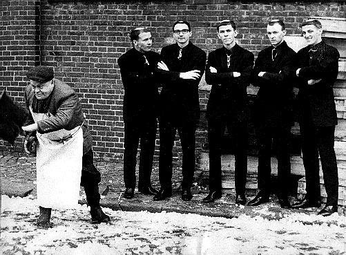 Rock band The Monks, standing with their arms folded, and another person