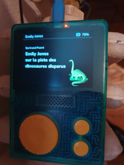 Face du Flam avec un livre chargé « Émilie Jones sur la piste des dinosaures perdus » (offert avec le crowdfunding). La batterie est à 79% et l'appareil en charge.