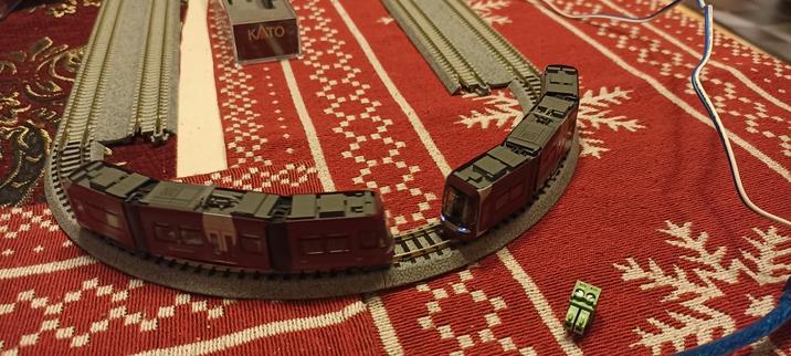 Zwei Straßenbahn Modelle in einer sehr engen Kurve auf einem Tisch mit weihnachtliche Tischdecke
