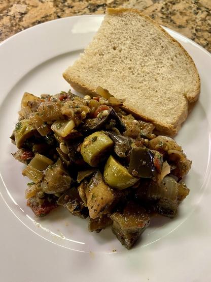 Caponata on a plate with a slice of bread
