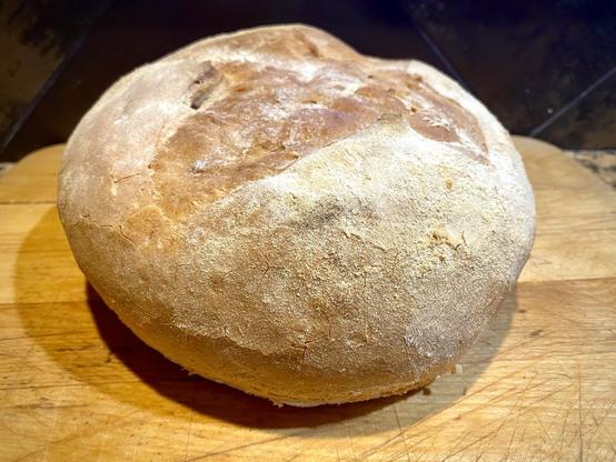 A whole round loaf of bread with a cross cut over the top.