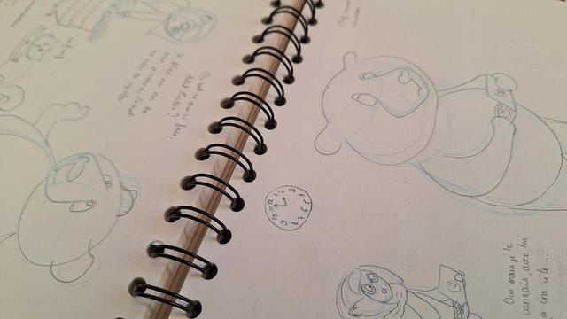 View of a sketchbook, with blue and grey pencil strokes.

Vue de mon carnet de croquis, avec des coups de crayons bleu et gris.