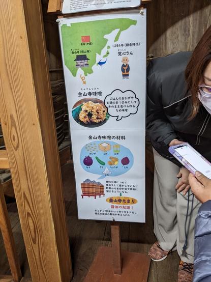 Narrow poster with cartoon map and illustration of items for soy sauce production.
A person is leaning forward to speak into a mobile device to translate