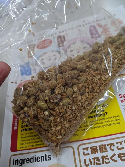A clear plastic bag with a mix of roasted cracked wheat and soy beans that have a film of koji on them