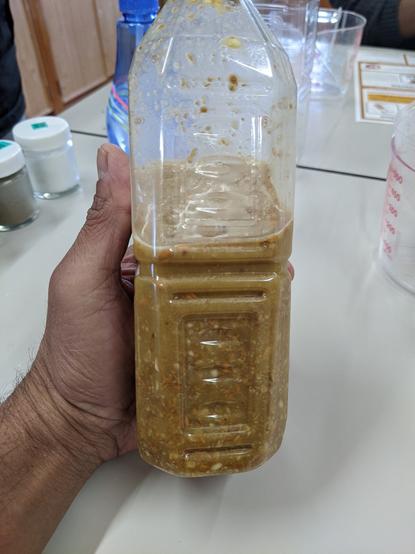 A clear plastic bottle with a brown slurry inside