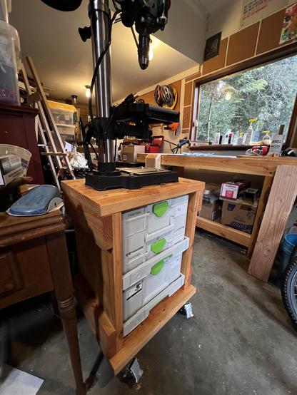 Cart with drill press on it in a dirty garage