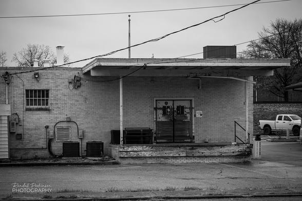 The back side of a 1 story commercial building with a loading dock and air conditioning equipment.