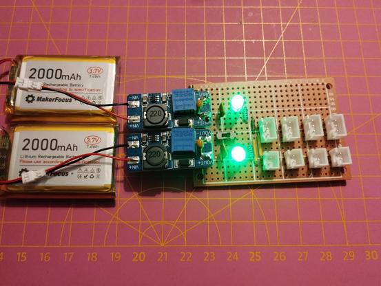 front of the finished perfboard with batteries and boost converters plugged in. the LEDs are lighting, indicating that the switch is turned on