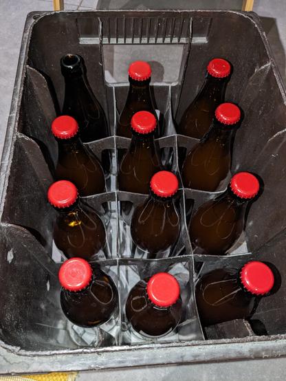 Une caisse de bouteilles de bière contenant les bouteilles avec leur jolies capsules rouges.