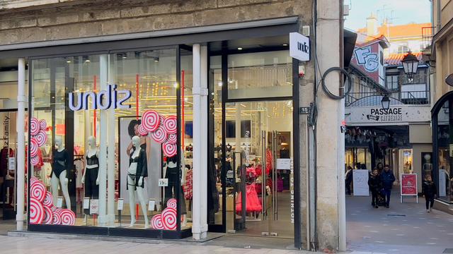 Store window with provocative name and reflections of street decorations