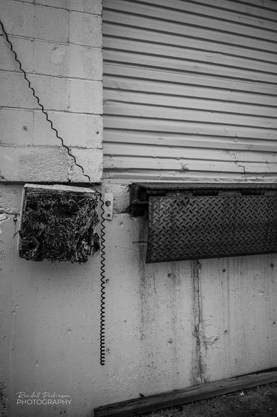 A portion of a loading dock door and associated rubber bumpers and a telephone type cord hanging from above.