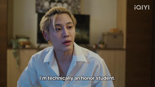 Buon Noppanut as Win, with short blond hair wearing a white shirt, looking to the side in a room, with subtitles that read, "I'm technically an honor student." The logo "iQIYI" is visible in the corner.