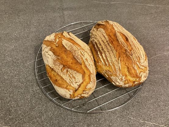 Two loaves of freshly baked bread on a wire cooling rack.