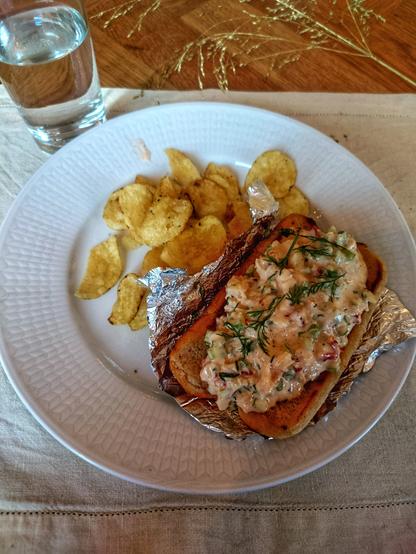 A plate with potato chips and home made lobster roll.