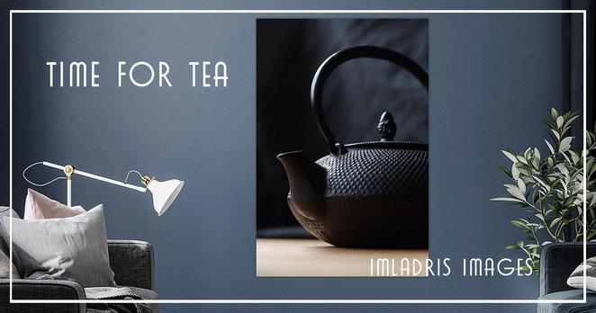 A black teapot in close up, sidelit, standing on a wooden table.