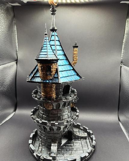 A right facing view of a 3d printed dice tower that is made to look like a miniature castle with a blue roof.