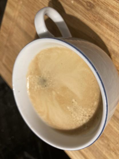 Eine Tasse Americano auf nem Holzbrett.