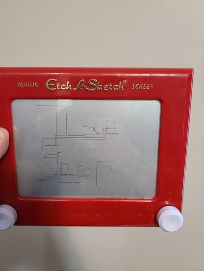 Image of a white person's hand holding a red bordered Etch A Sketch toy. On the grey screen of the Etch A Sketch, in blocky letters, is written "I Love Sleep."