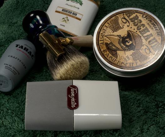 A Dogclaration B3 brush, a Schick G1 razor, a tin of Schmiere Abschaum soap, a bottle of Stirling Mountain Man splash, and a bottle of Tabac original craftsman frag
